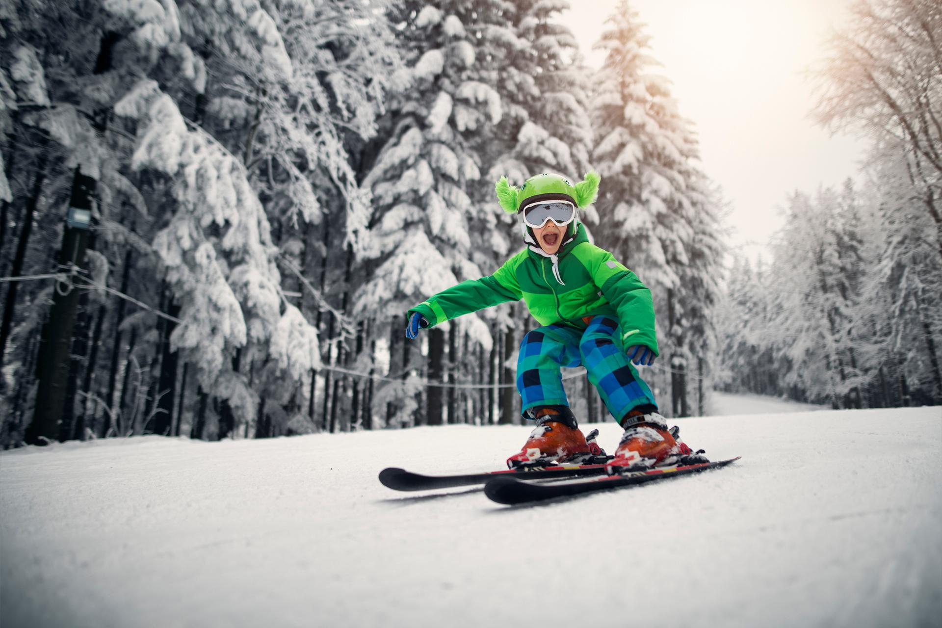 Child with ski down between trees in a ski resort