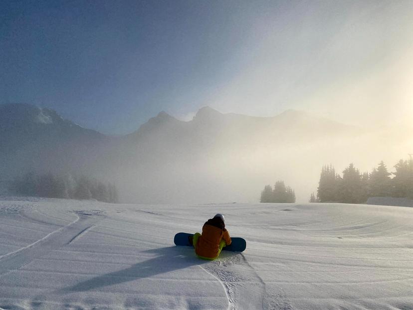Snowboarder getting ready to drop into ski slope on a misty day